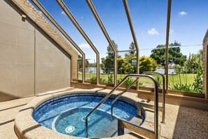 A hot tub with a view of a garden and a building in the background. - Lakeside Country Club - Numurkah (Numurkah)
