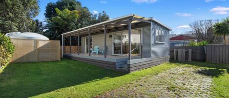 A single-story house with a covered patio, a fenced yard, and a paved driveway.