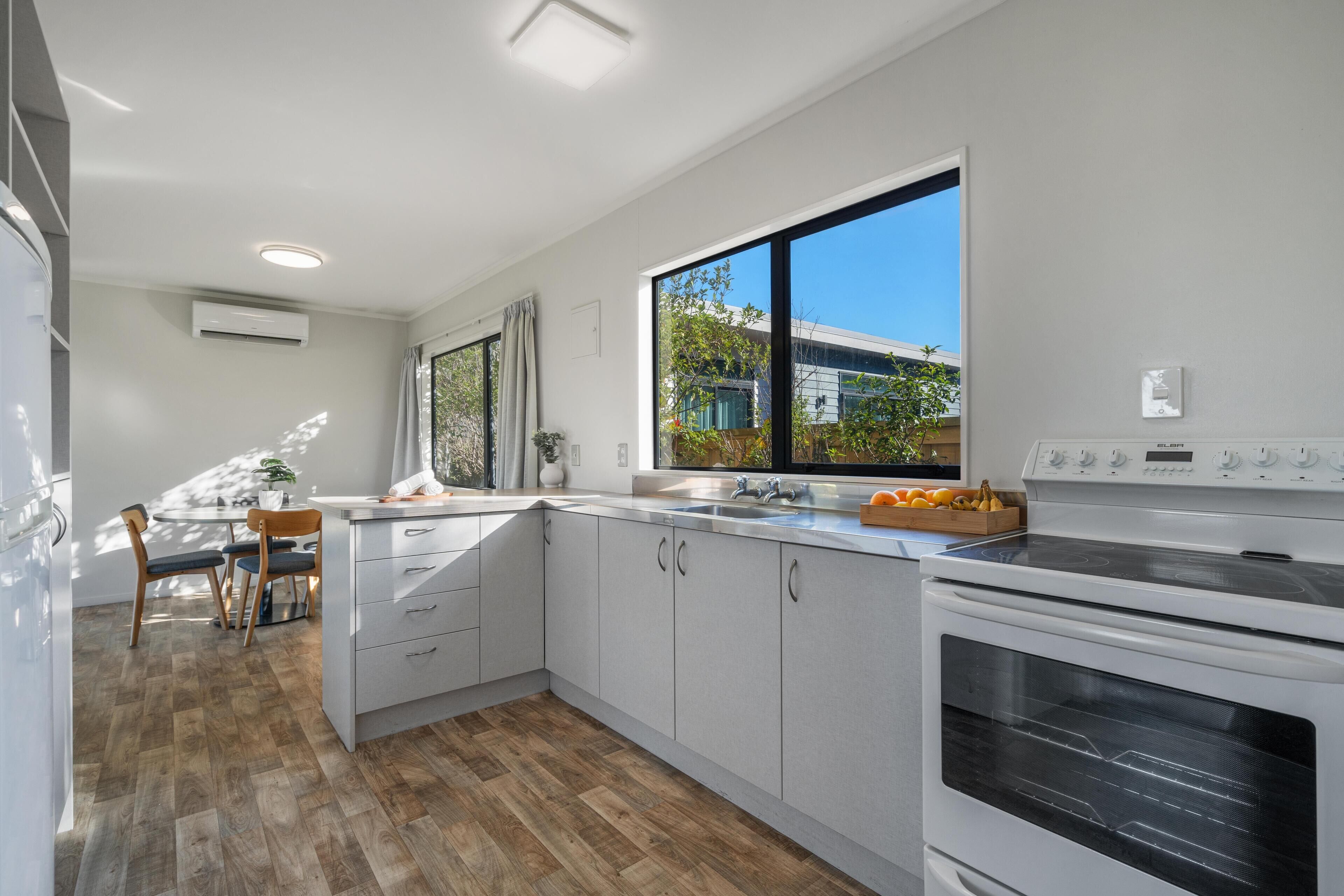 A modern kitchen with white cabinets, a large window, and a built-in oven.