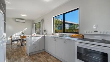 A modern kitchen with white cabinets, a large window, and a built-in oven.