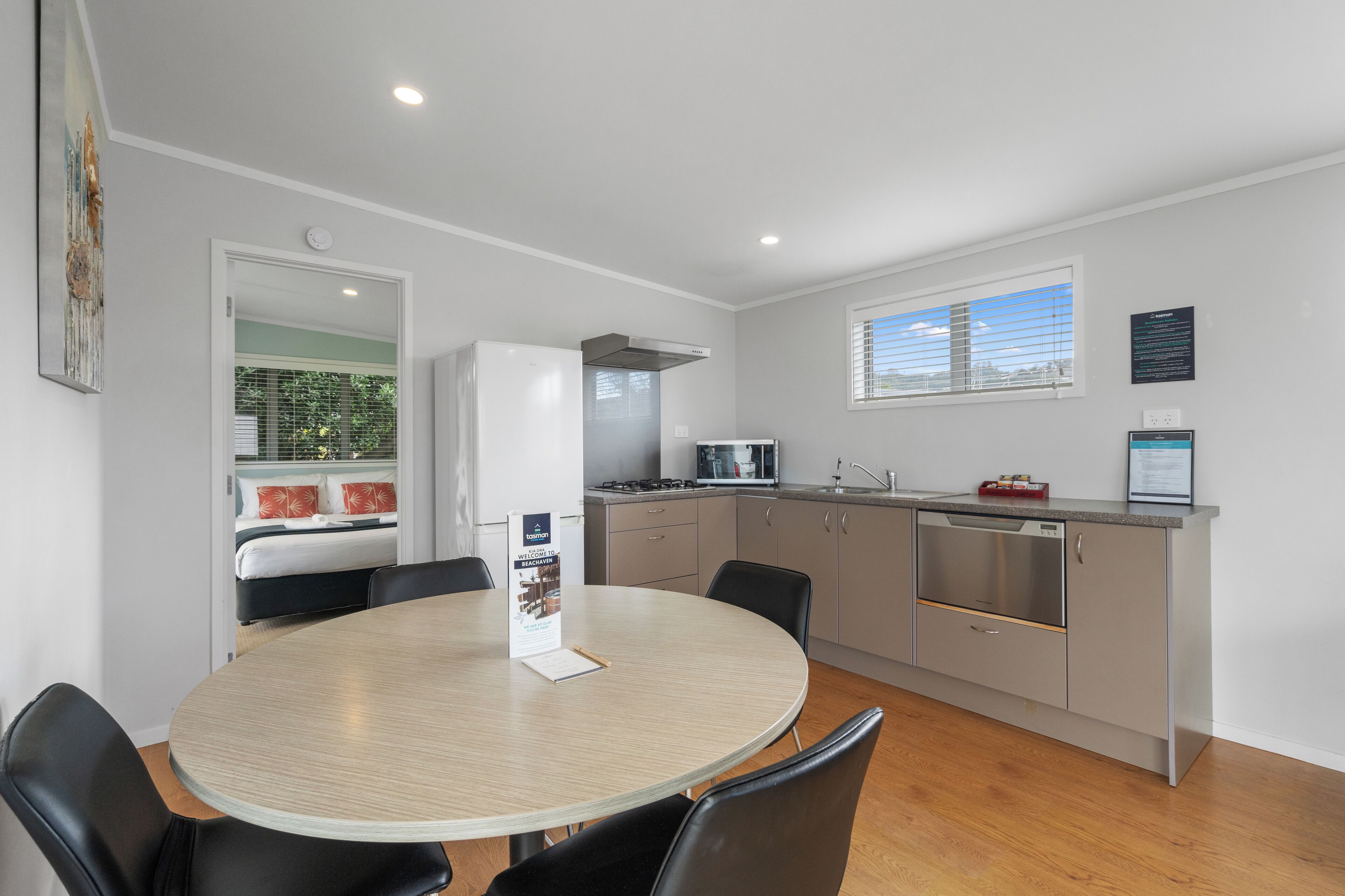 A modern kitchen with a dining area, featuring a round table, chairs, and a built-in oven.