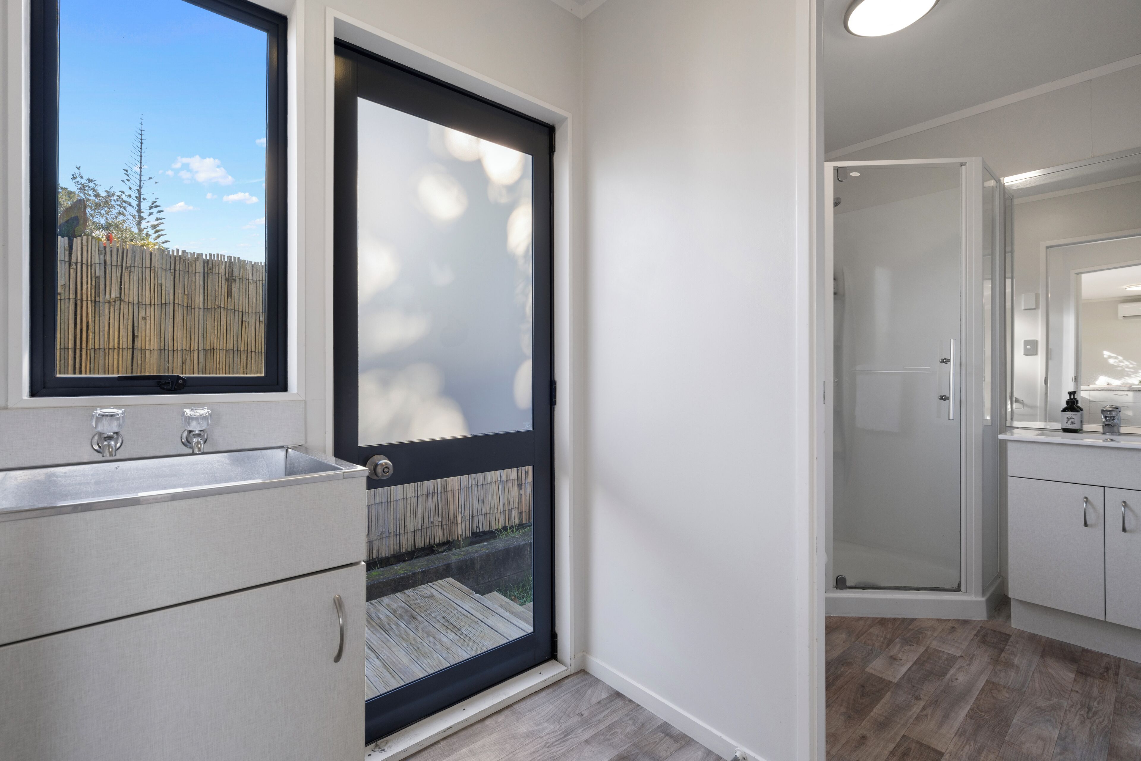 A modern bathroom with a large window, a shower, and a sink.