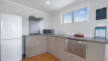 A modern kitchen with a refrigerator, microwave, stove, sink, and dishwasher.
