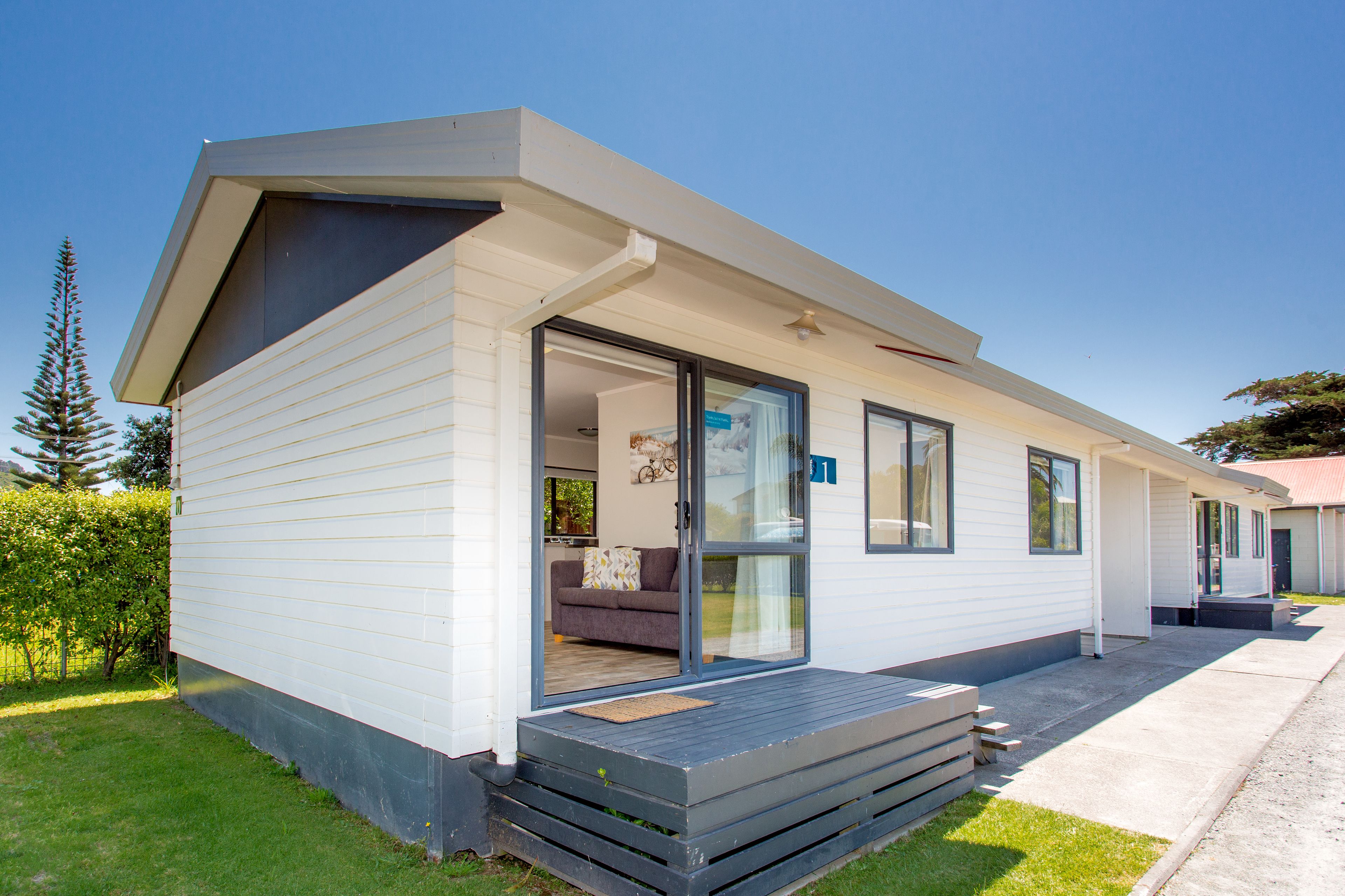 A modern mobile home with a sliding glass door entrance, a small porch, and a well-maintained lawn.