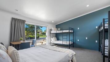 A modern hotel room with a large bed, a desk, a chair, and a bunk bed.