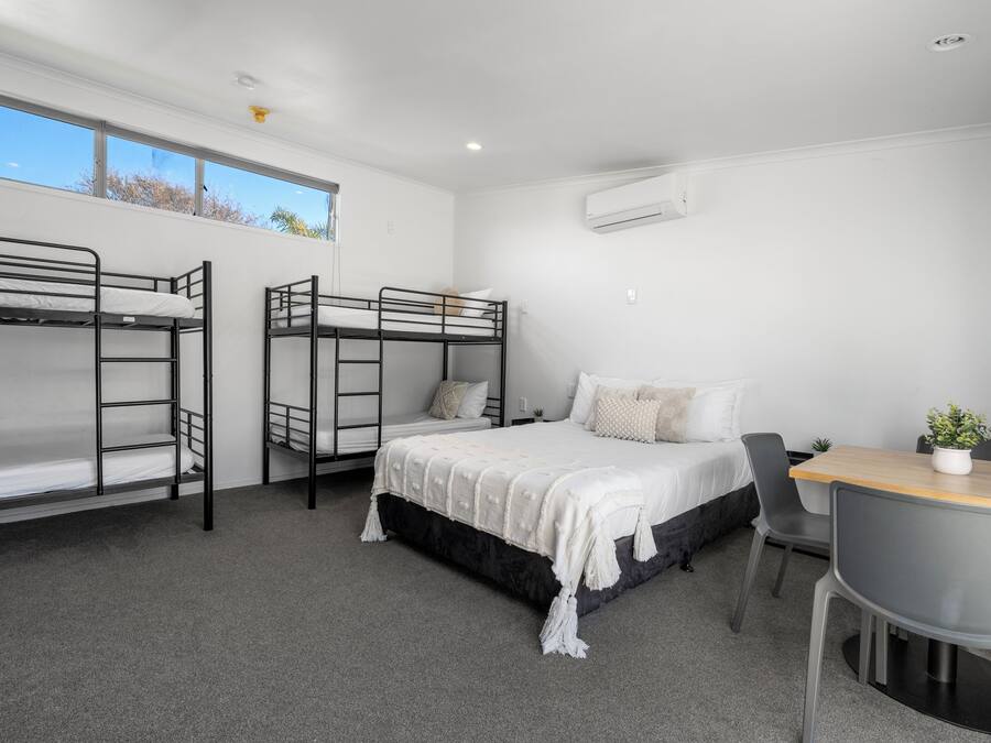A dormitory room with bunk beds, a desk, and a chair.