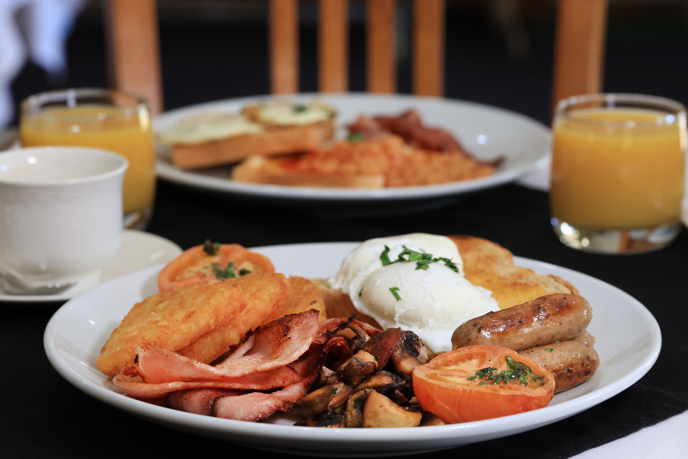 A breakfast plate with bacon, mushrooms, tomatoes, and toast.