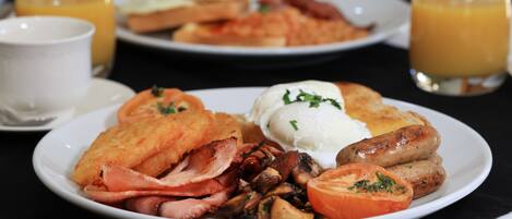 A breakfast plate with bacon, mushrooms, tomatoes, and toast.