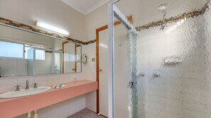 A bathroom with a pink vanity, two sinks, a mirror, and a shower with a glass door. - Chinchilla Great Western Motor Inn (Chinchilla)