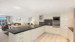 A modern kitchen with white cabinets, a black countertop, and stainless steel appliances. - Pandanus Mooloolaba (Mooloolaba)
