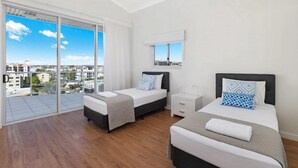 A modern hotel room with two beds, a large sliding glass door to the balcony, and a city view. - Pandanus Mooloolaba (Mooloolaba)