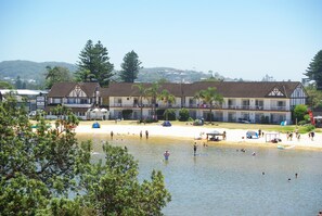 A lakeside hotel with a beach, swimming area, and a view of the surrounding hills. - The Clan Terrigal (Wamberal)
