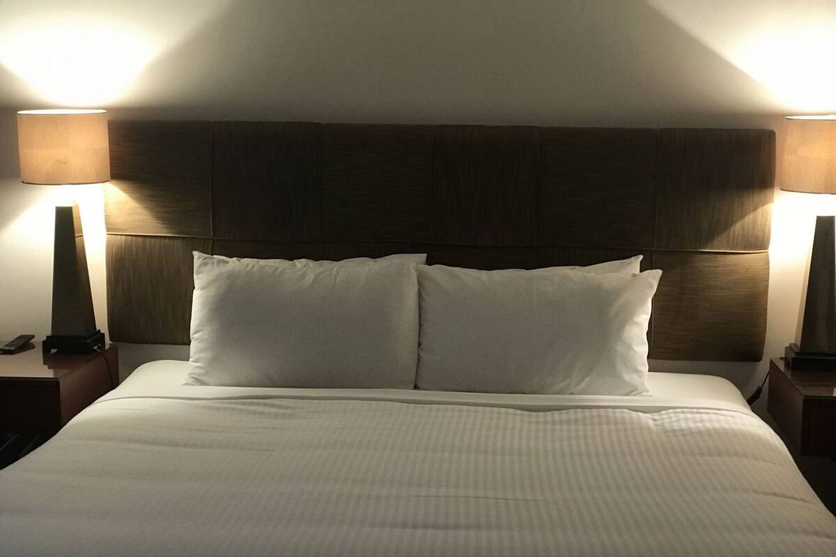 A hotel room with a large bed, two bedside lamps, and a wooden headboard.
