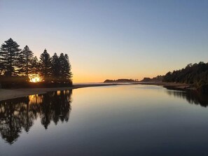 A calm lake at sunset with trees reflecting on the water. - The Clan Terrigal (Wamberal)