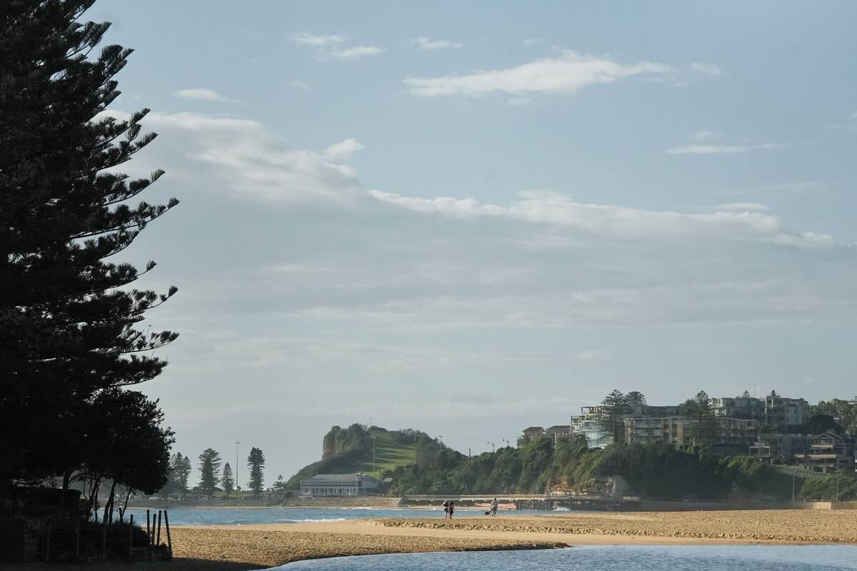 A beach with sand, water, and a few people.