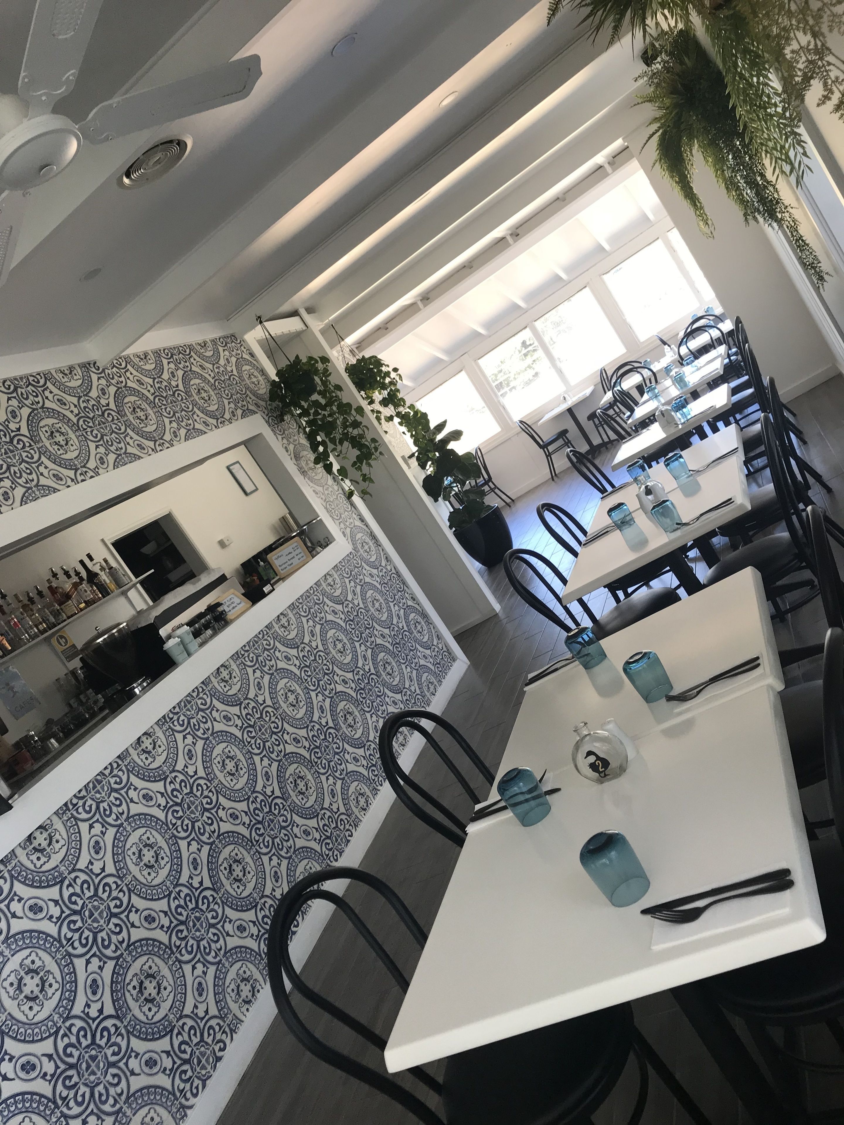 A modern dining area with patterned walls, a kitchen in the background, and a ceiling fan.