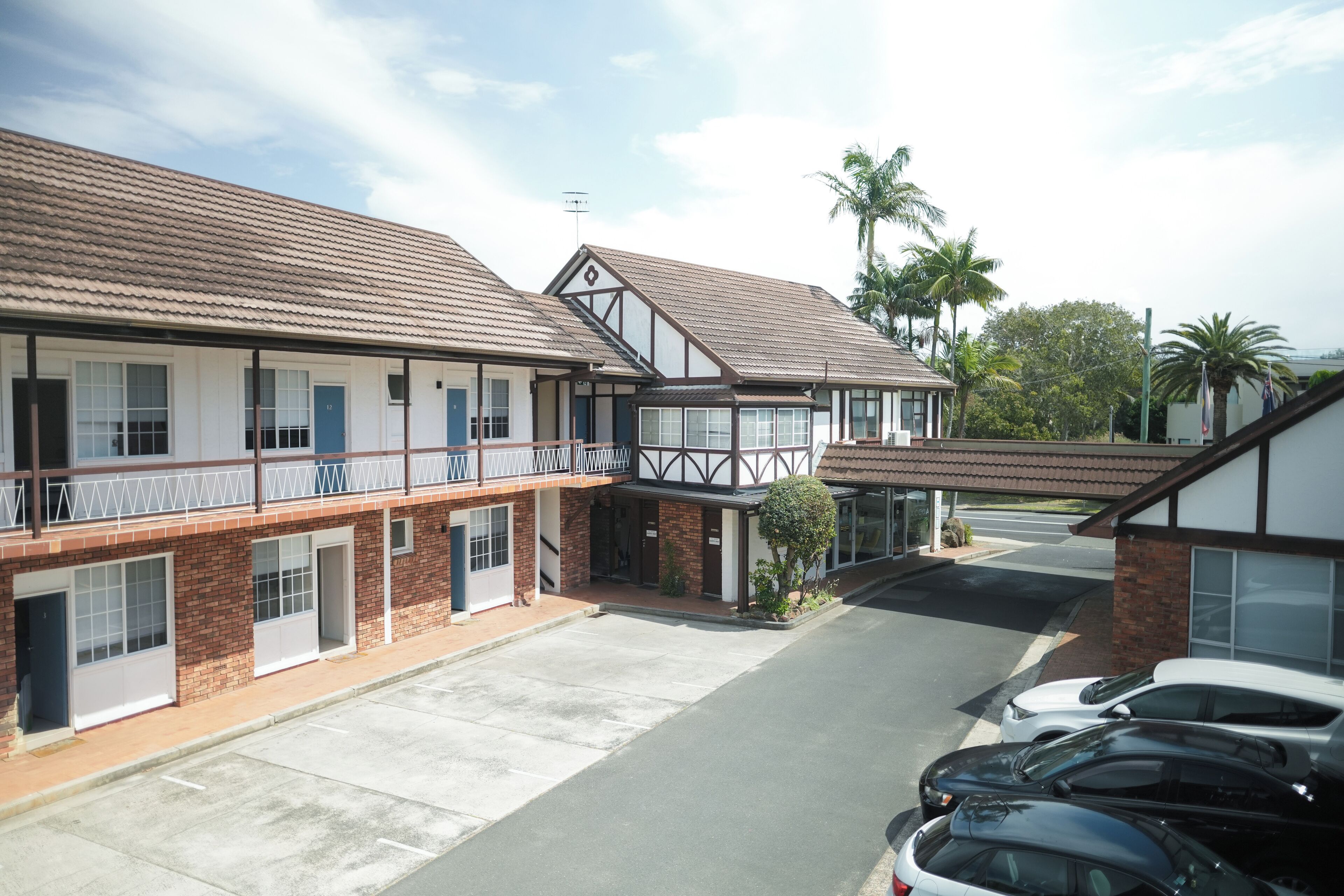 A two-story motel with a parking lot and a small garden area.