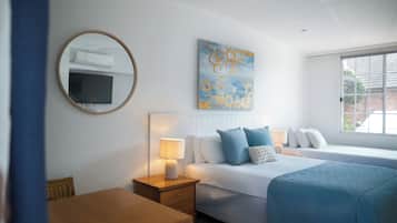 A hotel room with a bed, bedside tables, a mirror, a flat-screen TV, and a window.