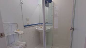 A bathroom with a glass-enclosed shower, a sink, and a towel rack with neatly folded towels.