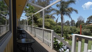 Una terraza cubierta al aire libre con barandillas blancas, sillas negras y una mesa.