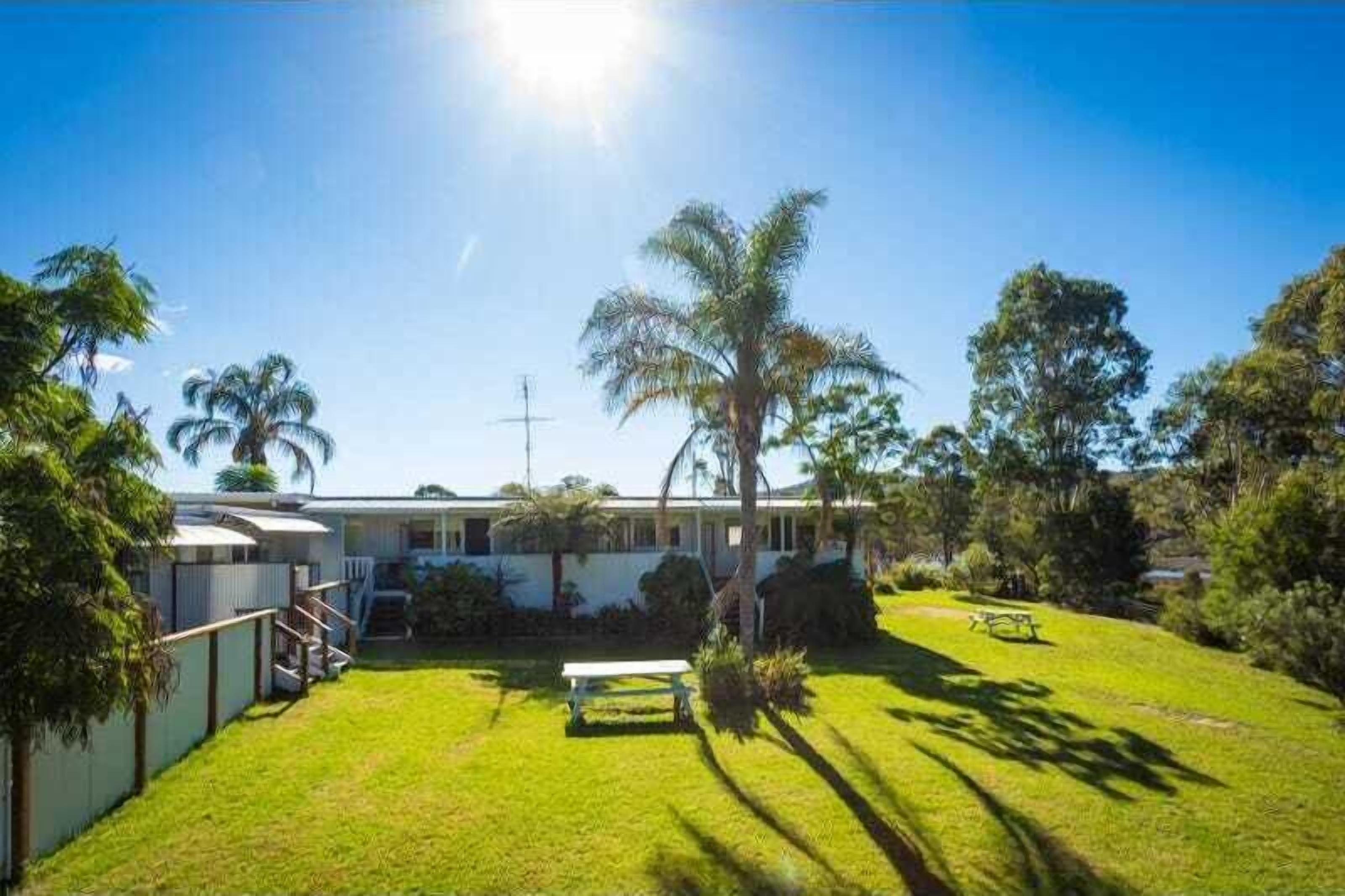 A residential property with a well-maintained lawn, a single-story house, and a small patio area.