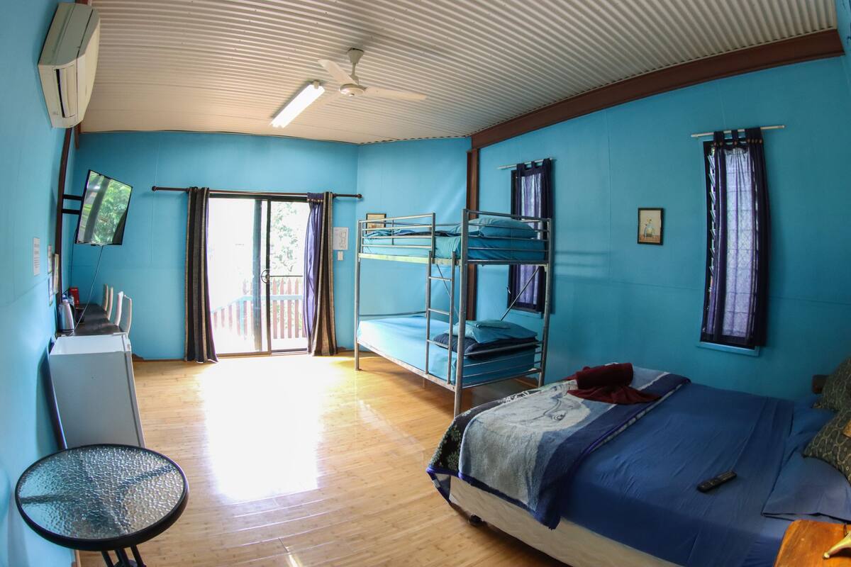 A room with bunk beds, a desk, a chair, and a television.