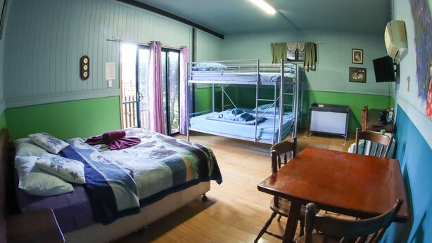 A room with bunk beds, a wooden table, and a television.
