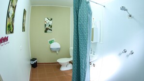 A bathroom with a toilet, sink, shower, and a green curtain.