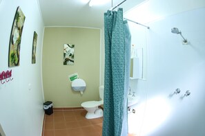 A bathroom with a toilet, sink, shower, and a green curtain.