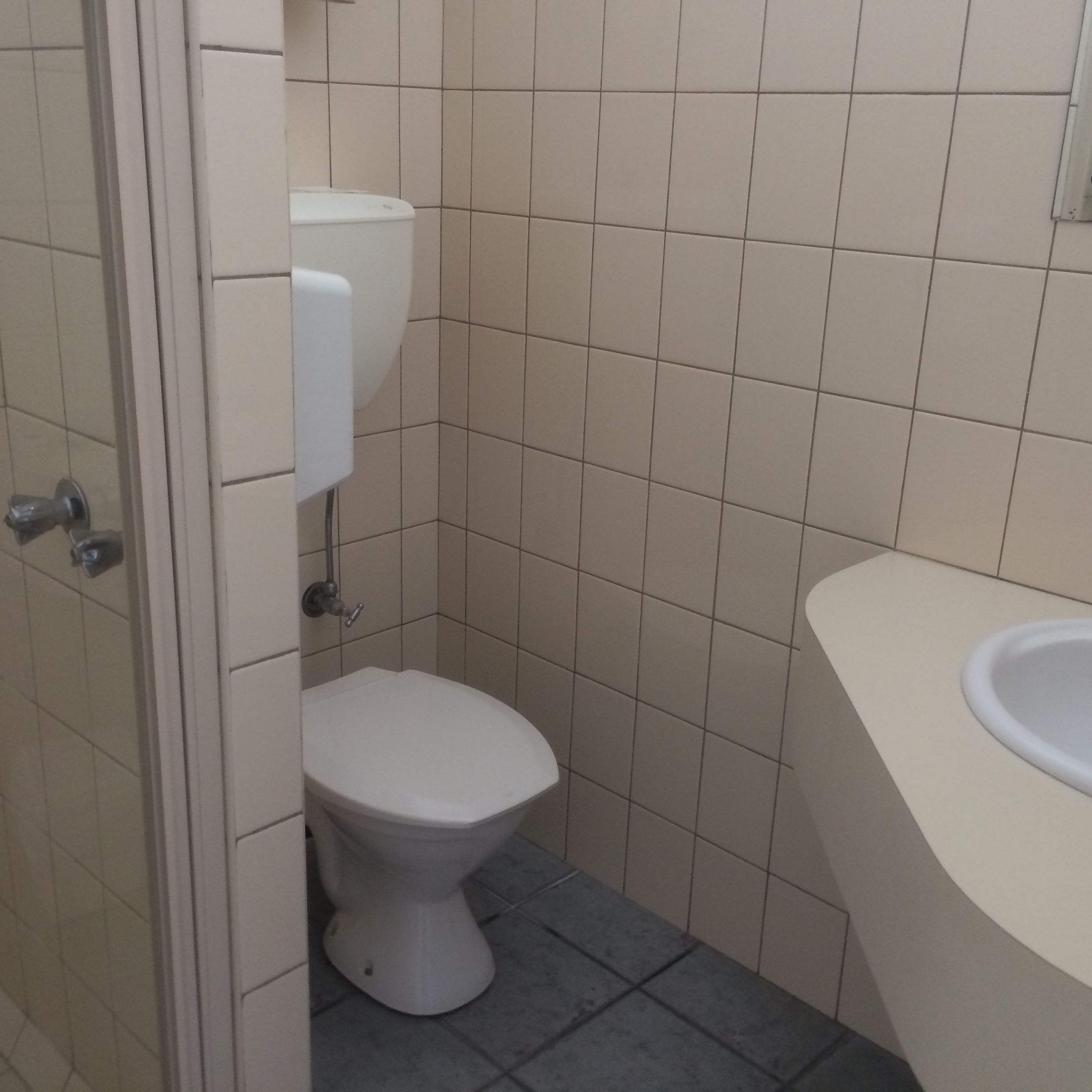 Un baño pequeño con inodoro, lavamanos y paredes con azulejos.