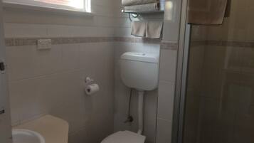 A small bathroom with a toilet, a towel rack, and a shower area.