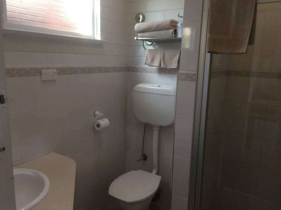 A small bathroom with a toilet, a towel rack, and a shower area.