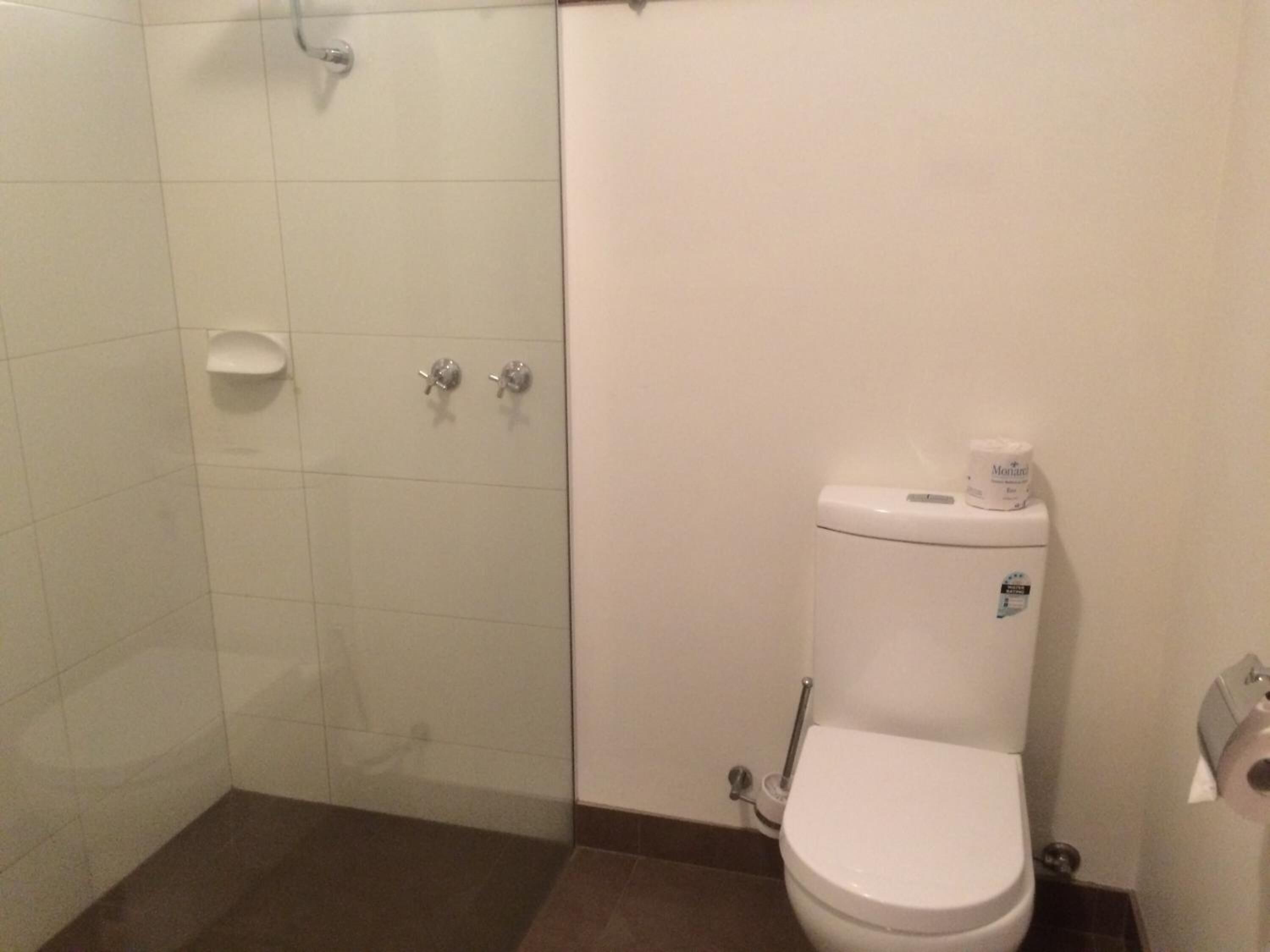 Ein Badezimmer mit Toilette, einer Duschkabine aus Glas und einem weißen Waschbecken.