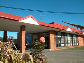 Un edificio con techo rojo, paredes de ladrillo y ventanas grandes.