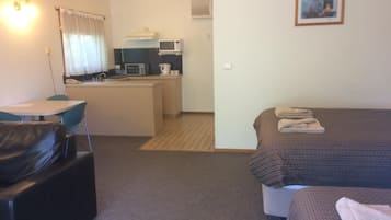 Una habitación de hotel compacta con kitchenette, comedor y cama.