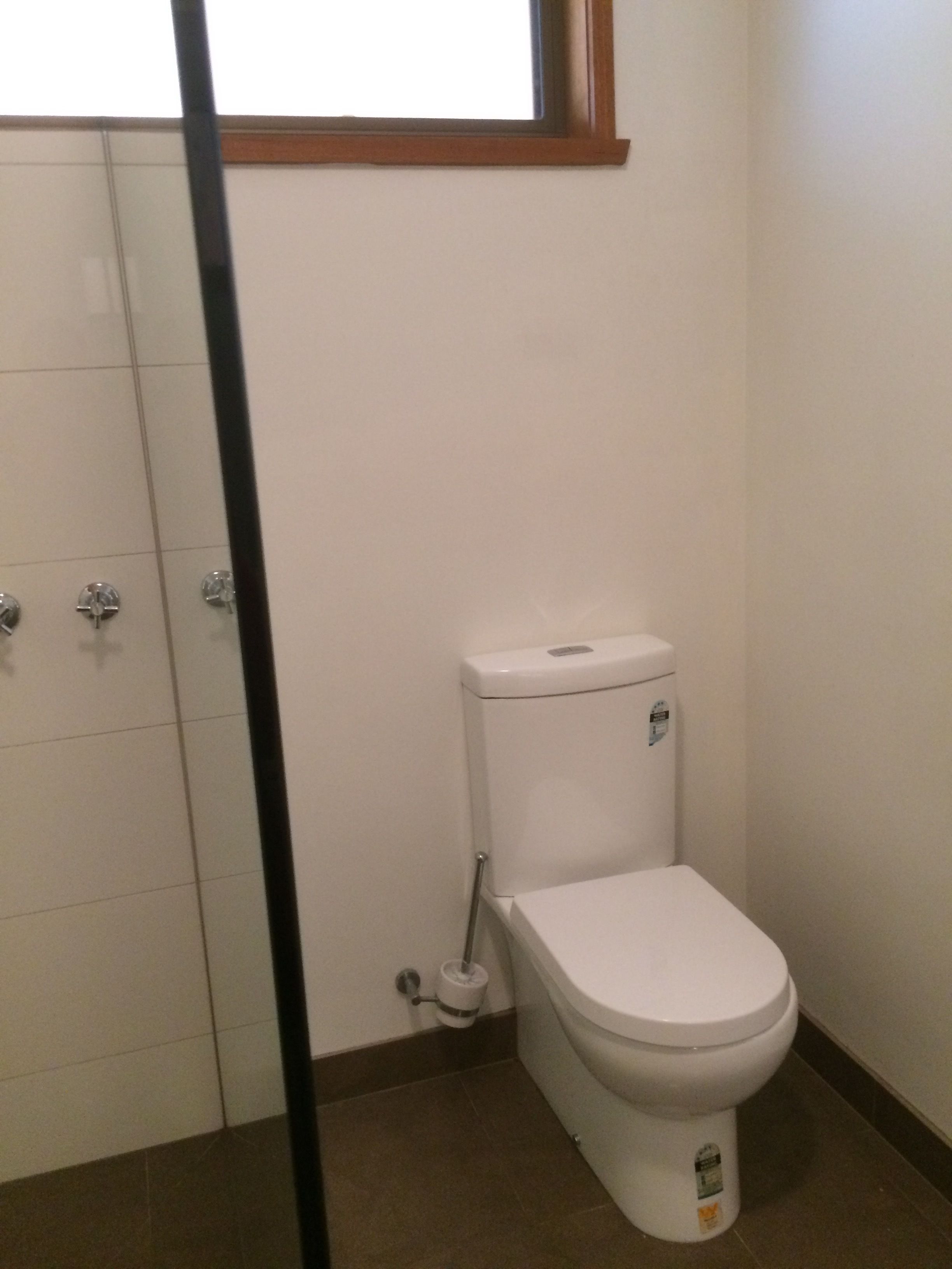 A small bathroom with a toilet, a bidet, and a window above the toilet.