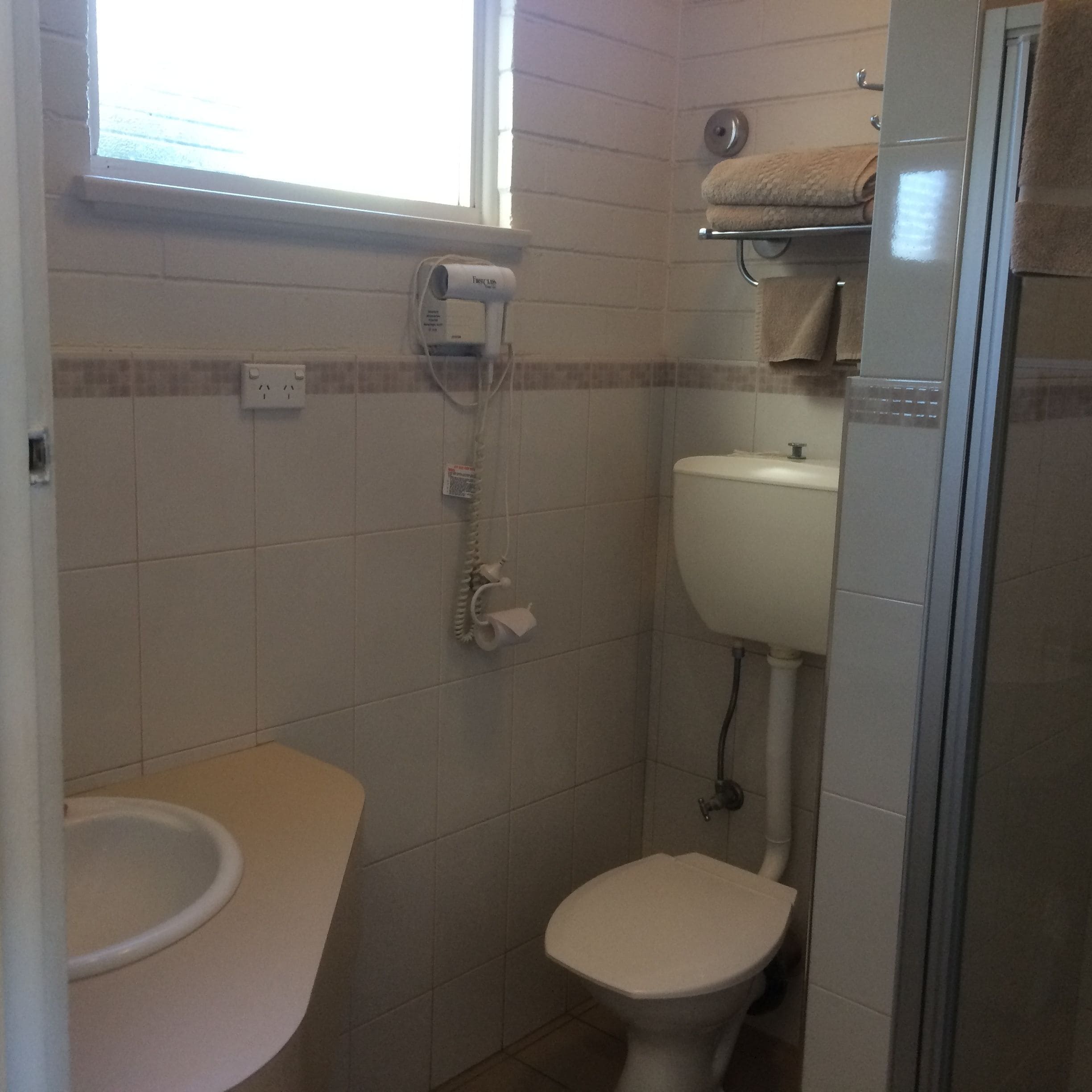 Une petite salle de bain avec des toilettes, un lavabo et un porte-serviettes.