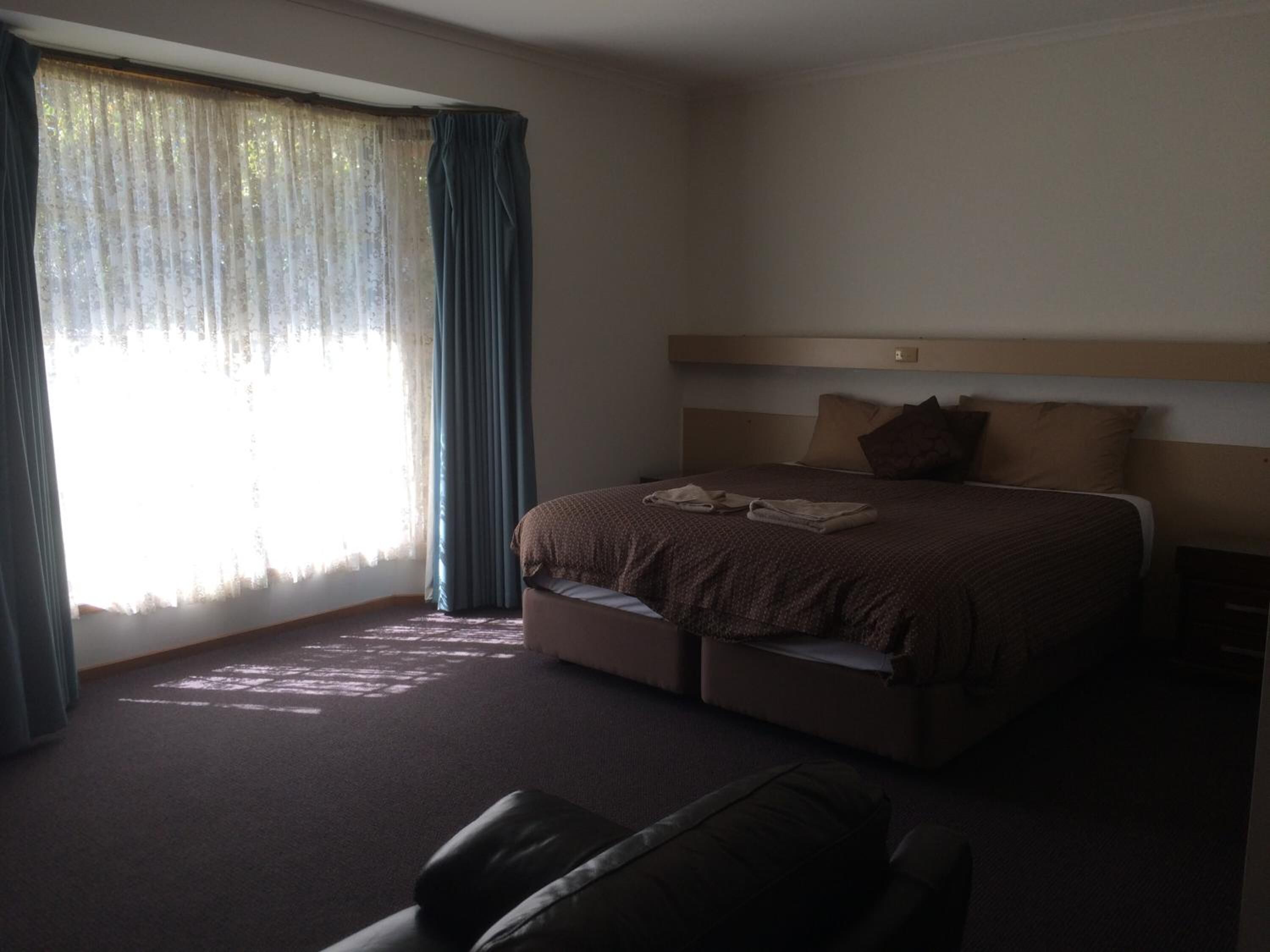 A hotel room with a large bed, a headboard, a desk, and a chair.