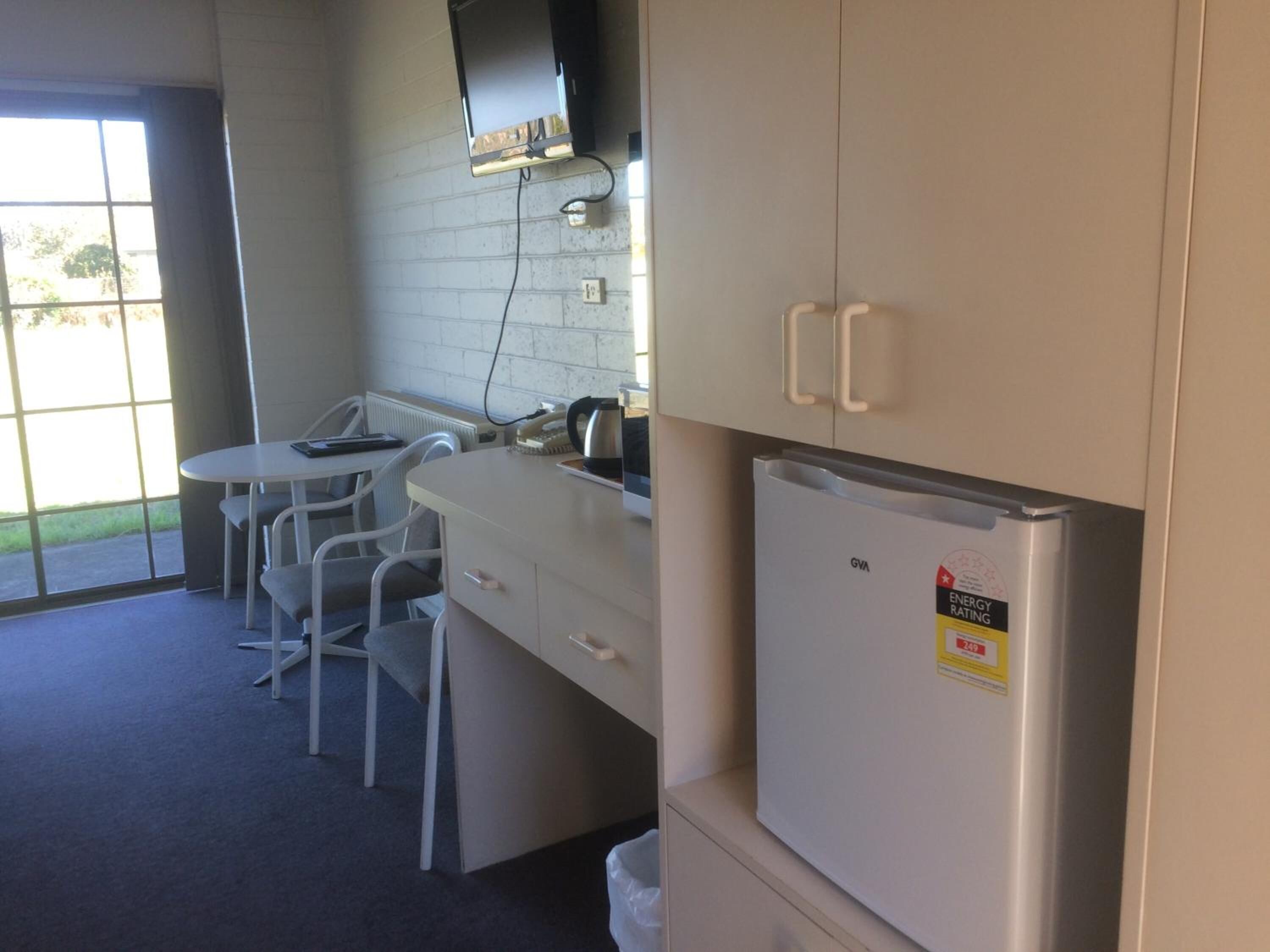 A compact kitchen with a refrigerator, a microwave, and a small dining area with chairs and a table.