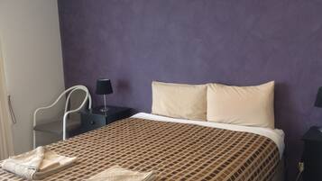 Een hotelkamer met een bed, een stoel, een nachtkastje en een lamp.