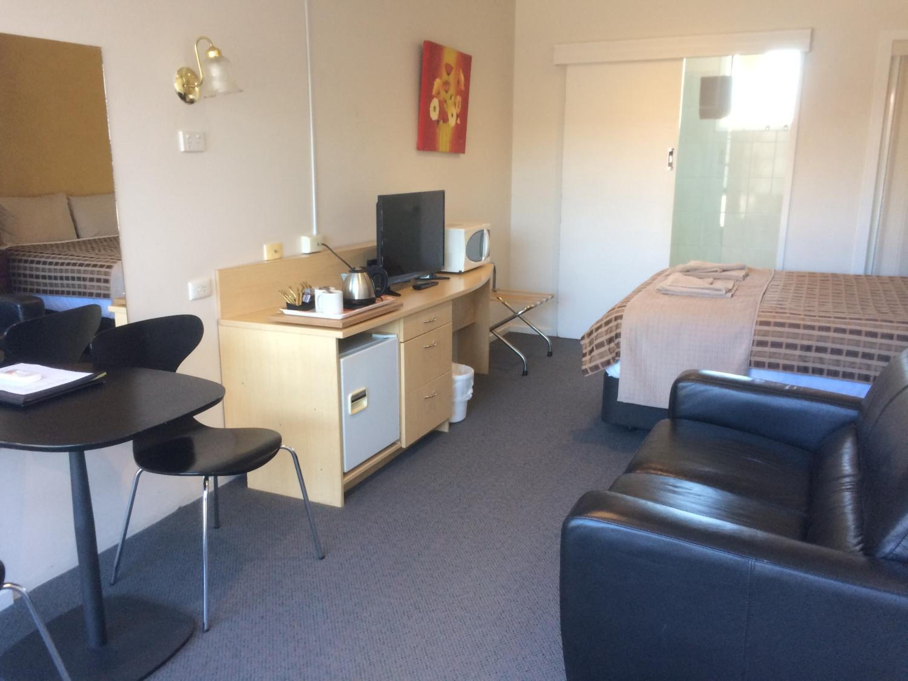 Una habitación de hotel con una cama, un escritorio con una computadora, una silla y un sofá.