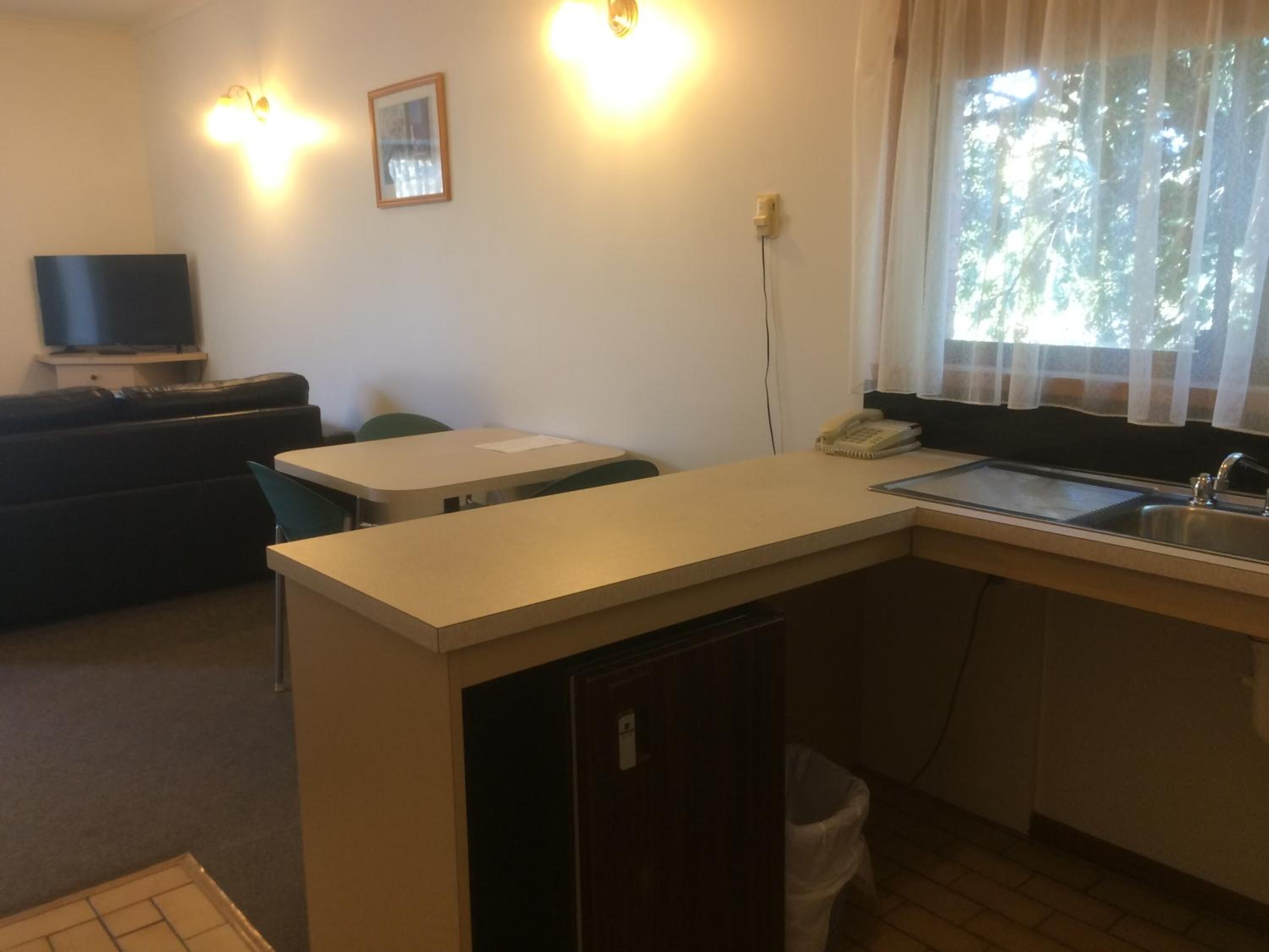A compact living space with a kitchenette, a sofa, a dining table, and a TV.