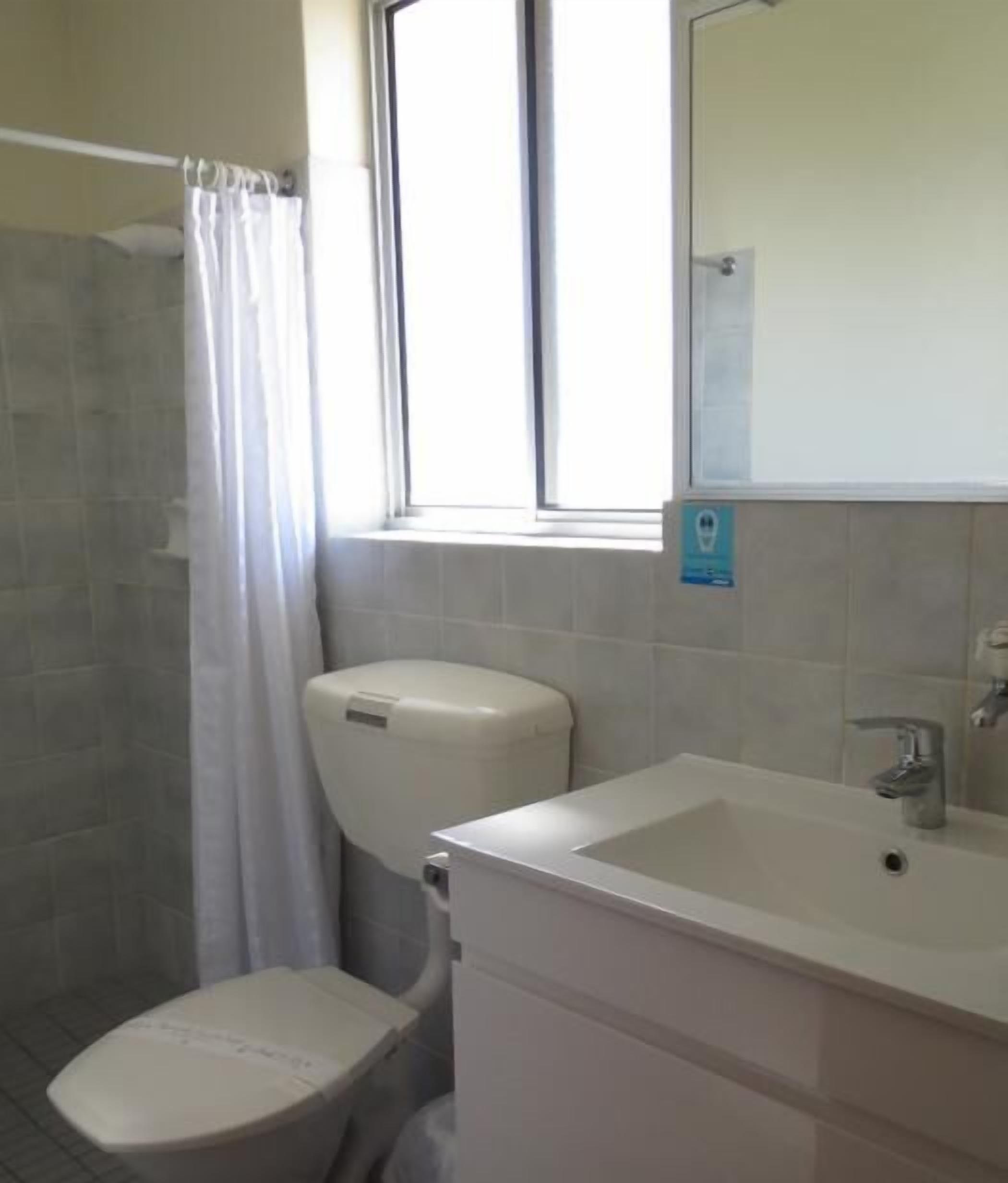 Un baño con inodoro, lavabo y zona de ducha.