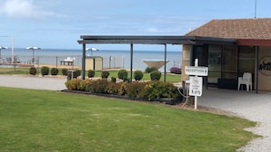 A reception area with a sign indicating a 10 mph shared zone, a pool, and a view of the sea. - Stansbury Holiday Motel (Stansbury)