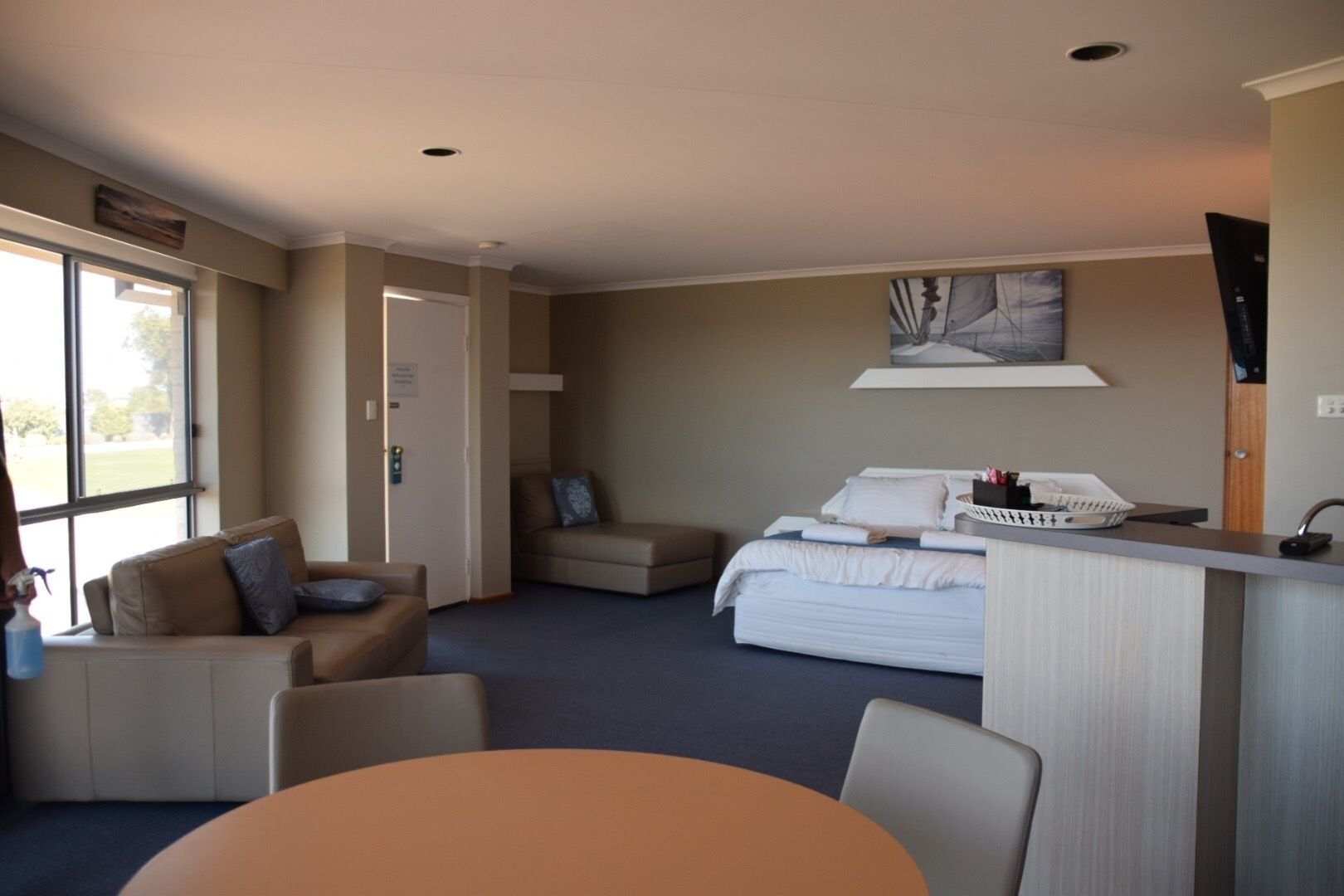 Ein Hotelzimmer mit einem Bett, einer Sitzecke mit Tisch, einer Küchenzeile und einem großen Fenster.