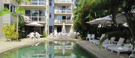 Alberca al aire libre, sombrillas en la alberca y camastros