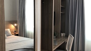Une chambre moderne avec un lit, une armoire en bois, un bureau et une chaise.