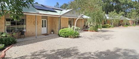 A building with a gravel driveway, a covered outdoor seating area, and a solar panel on the roof.