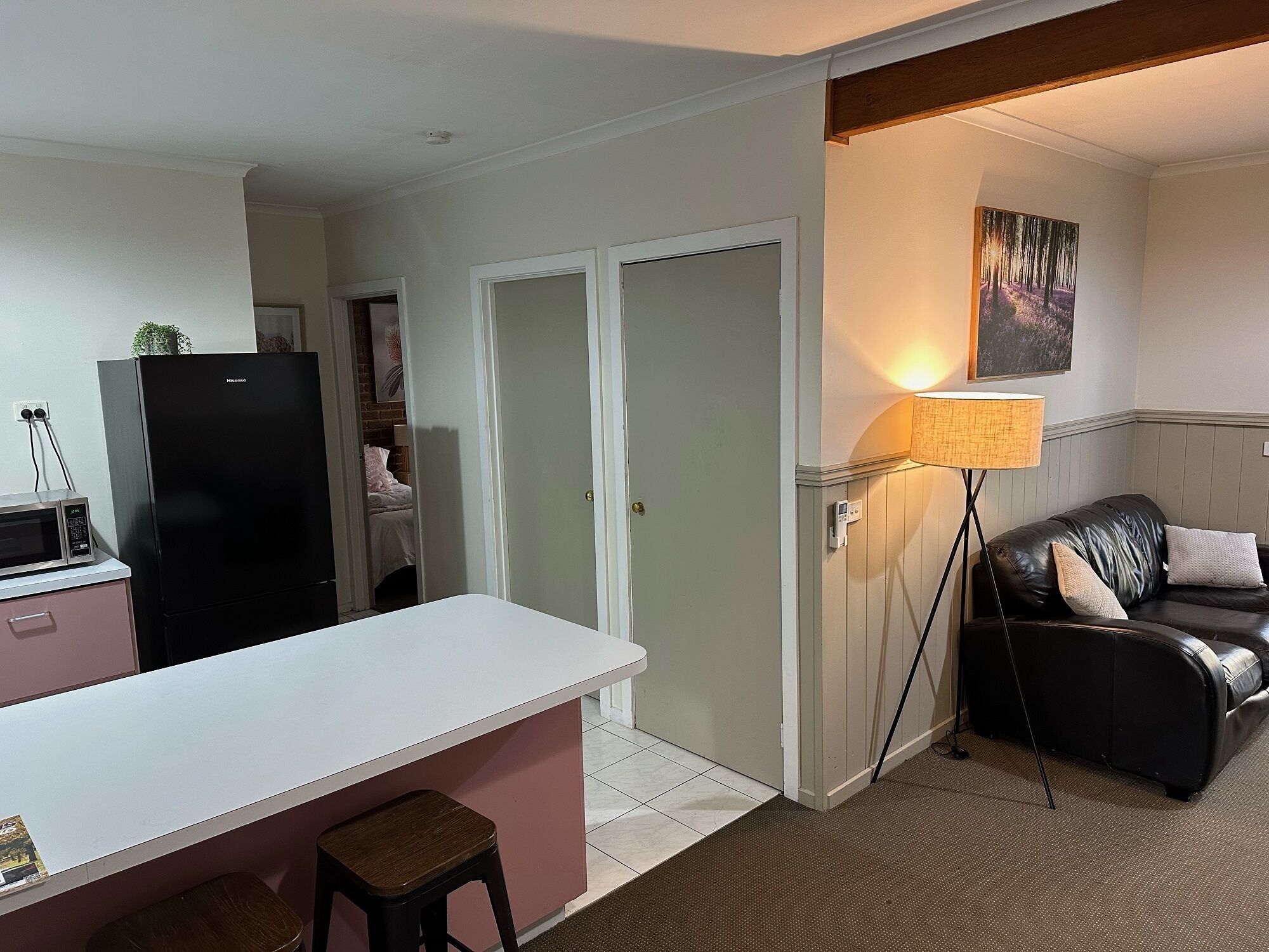 Um espaço de estar compacto com cozinha compacta, área de refeições, sala de estar com sofá e uma porta que dá para outro quarto.