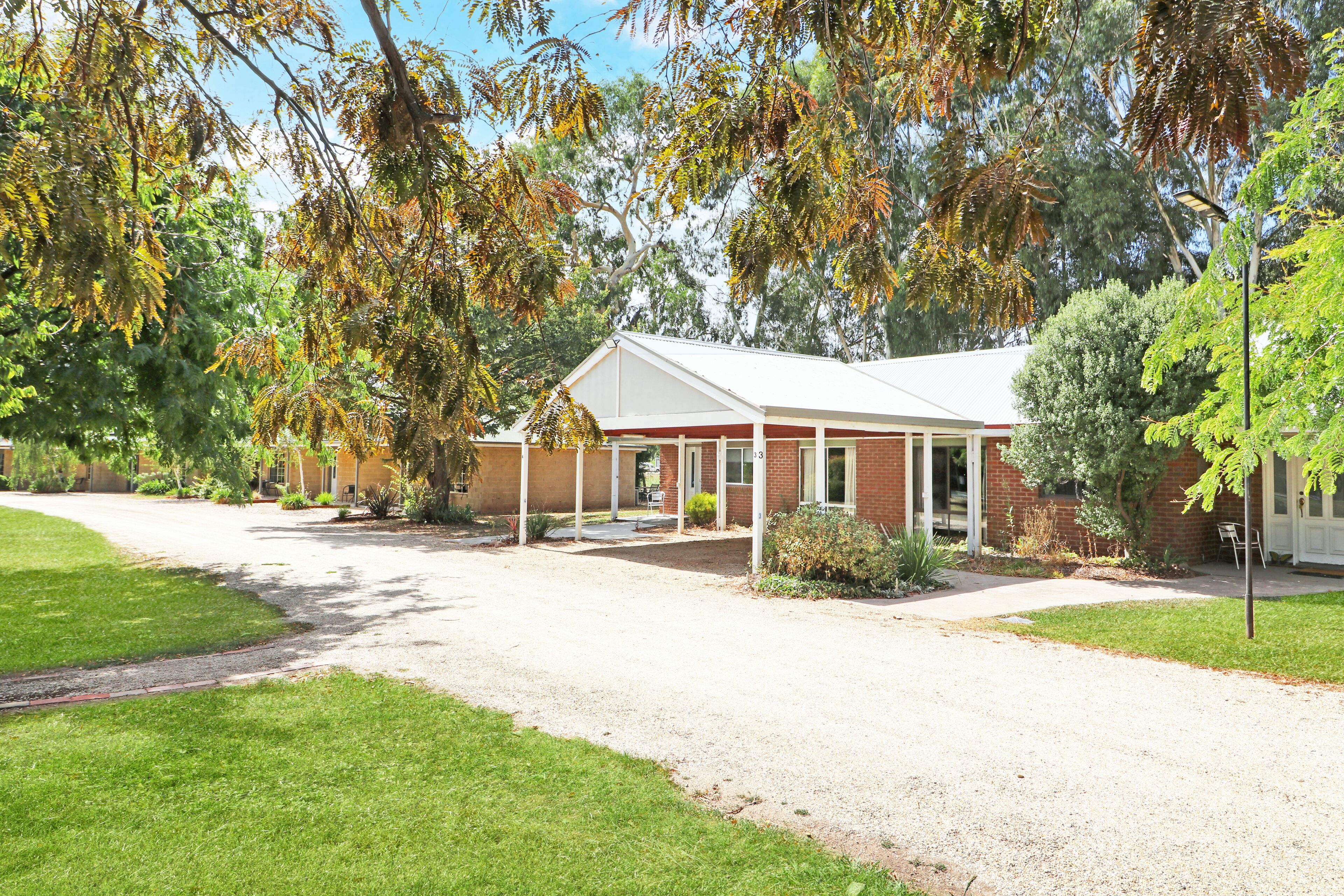A single-story building with a covered porch, surrounded by well-maintained lawns and mature trees.